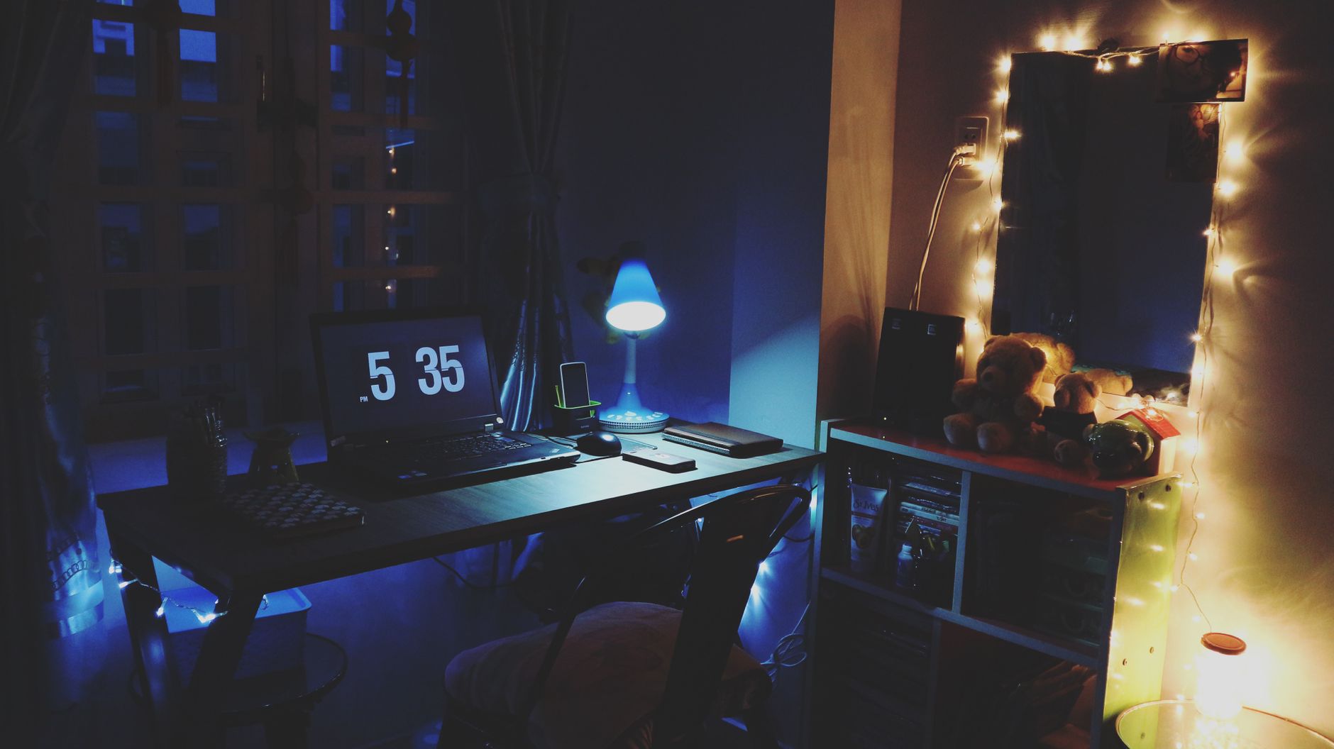 Een warm verlicht bureau in de avond met een laptop en sfeerverlichting, een typische thuiswerkplek.