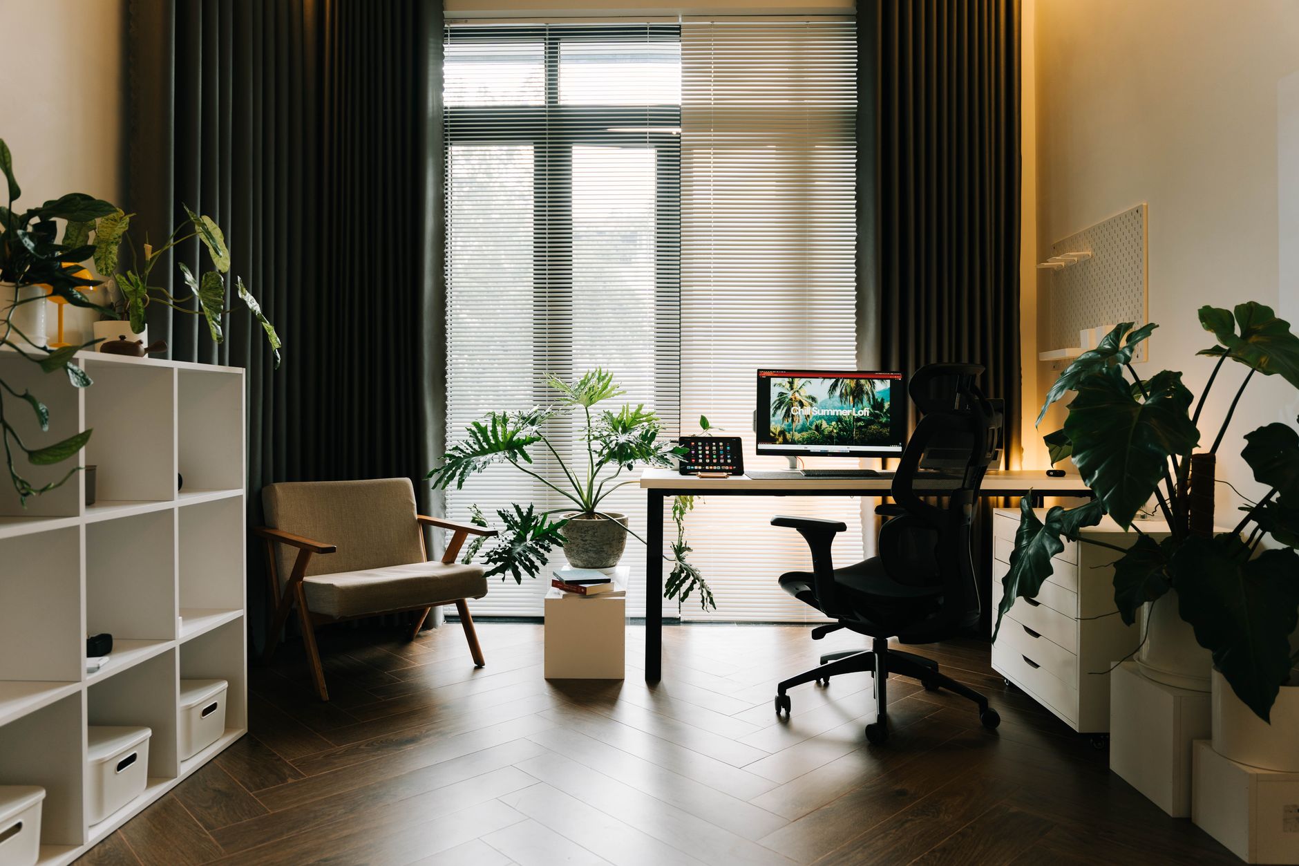 Een stijlvol thuiskantoor met modern meubilair en veel groene planten.