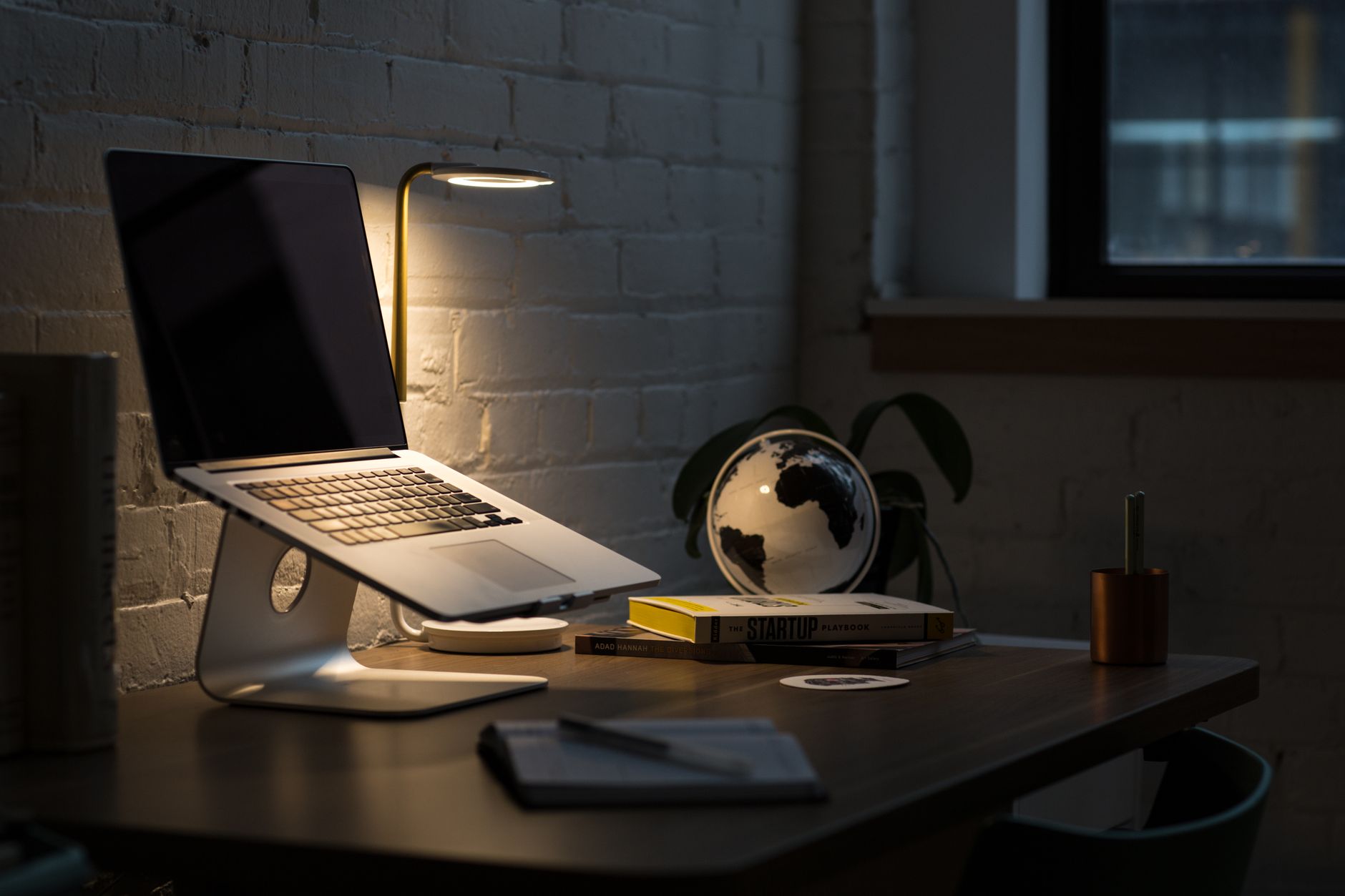 Een moderne werkplek met laptop, boeken en sfeervolle verlichting voor een productieve werkomgeving.
